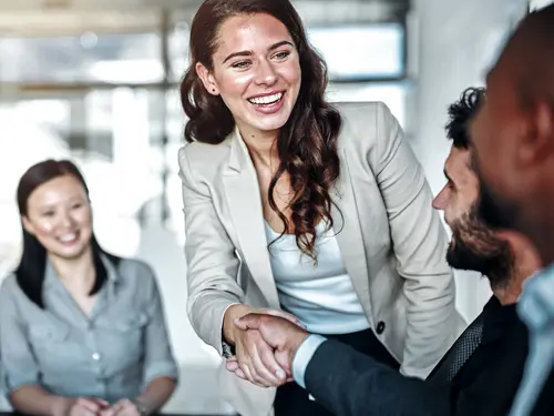 A woman shakes hands with a man and two other people