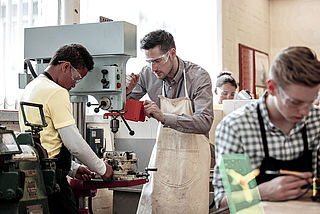 Eine Gruppe von Menschen arbeitet in einer Werkstatt an einer Maschine